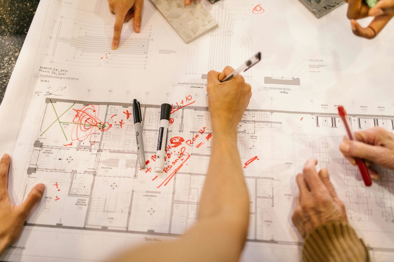 Hands explaining business strategies by writing on a plan to improve productivity and maximize potential.